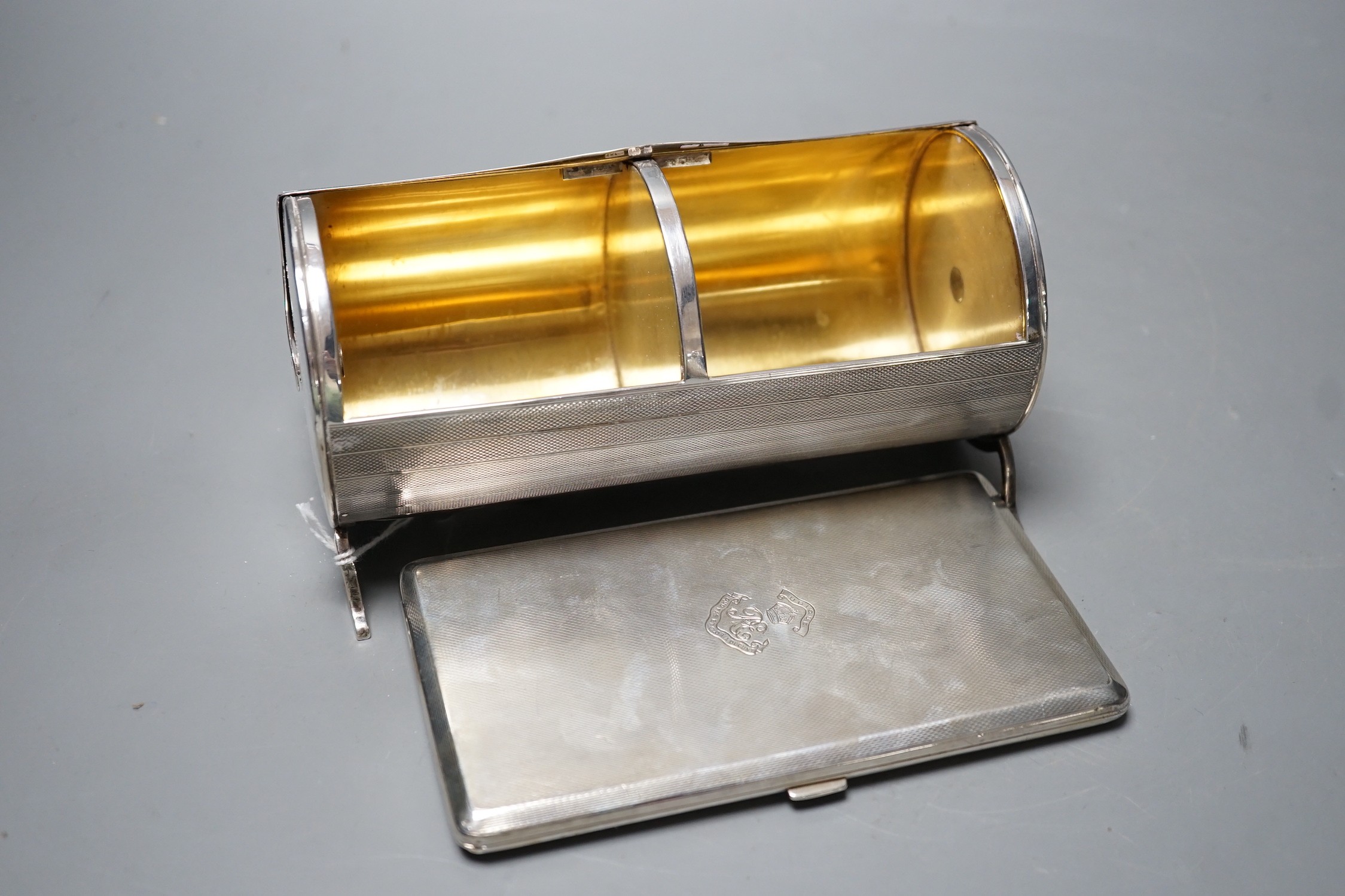 A George V engine turned cylindrical twin compartment cigarette box, with revolving cover, London, 1928, 17.1cm, with engraved inscription, together with a later large engine turned silver cigarette case, gross 21.5oz.